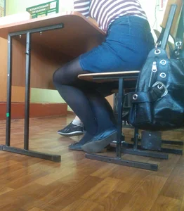 Crossed Legs of a Candid College Teen in a Denim Skirt Sitting at a Desk