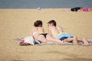 Sexy girl on the beach laying out and bending over in her bikini