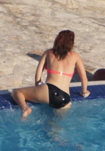 Sexy red haired girl in pink and black bikini at the pool