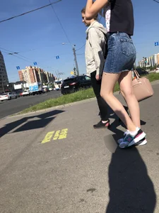Cute Girl in a Short Denim Skirt Walking on a Street And Waiting on a Crosswalk Gallery