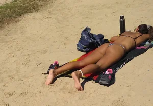 Sexy girl getting some sun laying on the beach in thong bikini