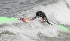 Brunette bikini girl on the beach and surfing in her bikini