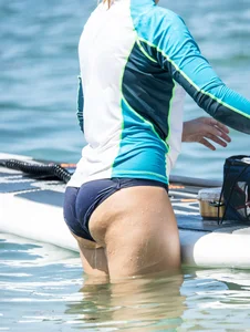 Girl in the water in a navy blue bikini bottom, shirt and hat with a nice ass