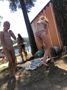 Young Skinny Girl Taking Off Her Denim Shorts Leaving a Swimsuit - Bending Over While Laying a Blanket on the Ground at a Lake Nature Park Gallery