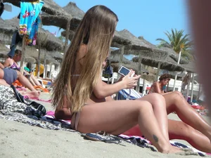 Tattooed babe at the beach with a nice round ass in little thong bikini