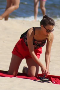 Hottie undressing from her red shorts to her bikini to layout on the beach
