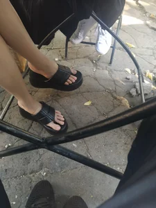Girl’s Crossed Skinny Legs And Feet in Slippers Under Street Cafe Table Creepshot