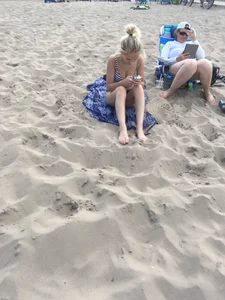 Young Blonde Girl in a Swimsuit Sitting at the Beach