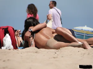 Topless lady on the beach in a gold thong with a nice ass
