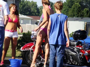 Group of cute girls at a car wash in bikinis and shorts
