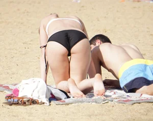 Sexy girl on the beach laying out and bending over in her bikini