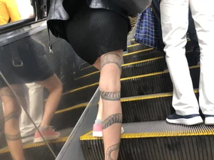 Girl in a Skirt With a Snake Tattoo on Her Leg Standing With Spread Legs on an Escalator Creepshots Series