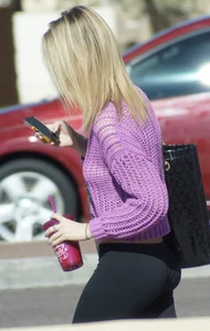 Beautiful skinny blonde in tight leggings and purple crop top showing sexy stomach