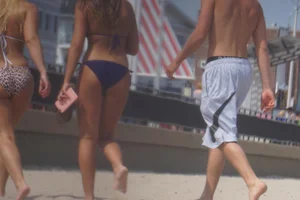 Two sexy friends, one blonde and one brunette, on the beach in bikinis