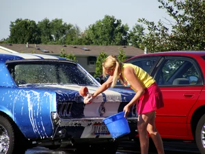 Group of cute girls at a car wash in bikinis and shorts