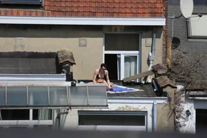 Neighbor on rooftop tanning in bikinis