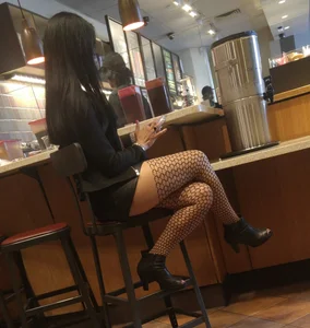 Girl in Mini Skirt And Pantyhose With Fishnet Pattern Sitting in a Cafe Candid Photo