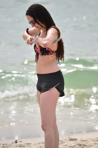 Brunette girl in black shorts and bikini top on the beach