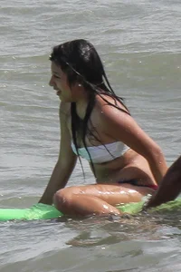 Brunette bikini girl on the beach and surfing in her bikini