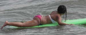 Brunette bikini girl on the beach and surfing in her bikini