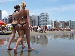 Two nice asses walking on the beach in black thong bikinis