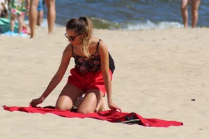 Hottie undressing from her red shorts to her bikini to layout on the beach