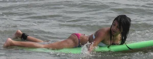 Brunette bikini girl on the beach and surfing in her bikini