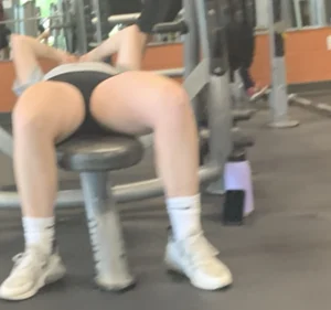 Fit Girl in Spandex Shorts Working Out With a Barbell While Lying With Spread Legs