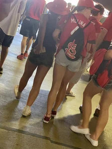Bunch of girls in various outfits at a Cardinals baseball game