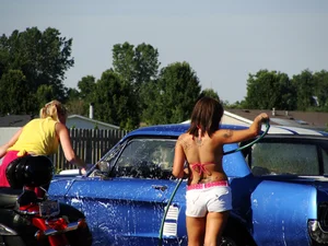 Group of cute girls at a car wash in bikinis and shorts