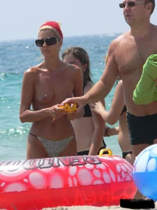 Topless skinny blonde lady in a g-string bikini at the beach