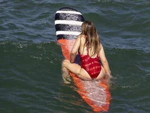 Hot surfer girl in a one-piece swimsuit in water