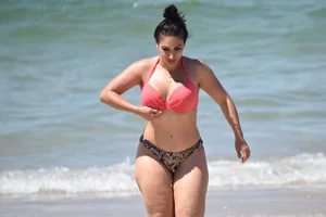 Huge boobed thick brunette babe on the beach in a bikini