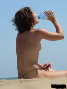 Topless beach milf looking sexy in a tiny g-string bikini