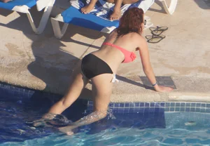 Sexy red haired girl in pink and black bikini at the pool