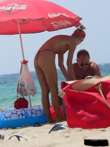 Topless skinny blonde lady in a g-string bikini at the beach