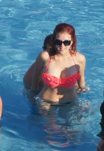Sexy red haired girl in pink and black bikini at the pool