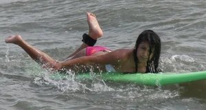 Brunette bikini girl on the beach and surfing in her bikini