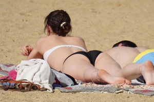 Sexy girl on the beach laying out and bending over in her bikini