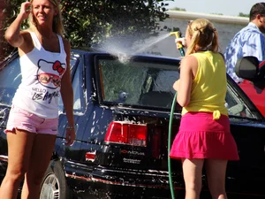 Group of cute girls at a car wash in bikinis and shorts