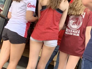 Bunch of girls in various outfits at a Cardinals baseball game