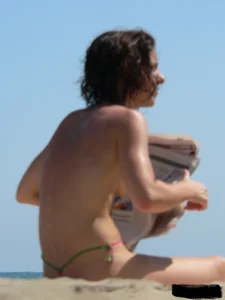 Topless beach milf looking sexy in a tiny g-string bikini