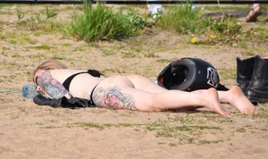 Tattooed Girl in Swimsuit Lying at the Beach with Motorcycle Helmet