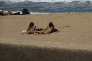 Two babes laying on the beach in bikinis with nice asses
