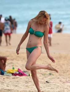 Sexy brunette in thong bikini and blonde friend in green bikini at the beach