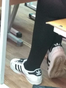 College Teen's Legs in Black Tights And Feet in Sneakers Photo in Class
