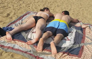 Sexy girl on the beach laying out and bending over in her bikini