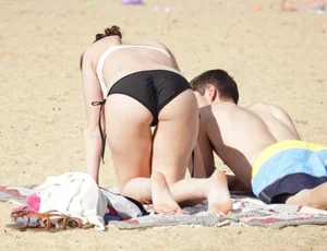 Sexy girl on the beach laying out and bending over in her bikini