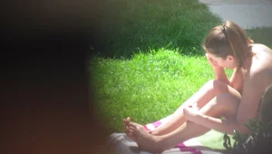 Cute Girl in a Swimsuit Sitting on Grass