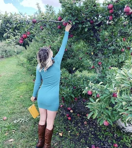 Girl in a Short Dress And Knee High Boots Reaching Out to a Tree